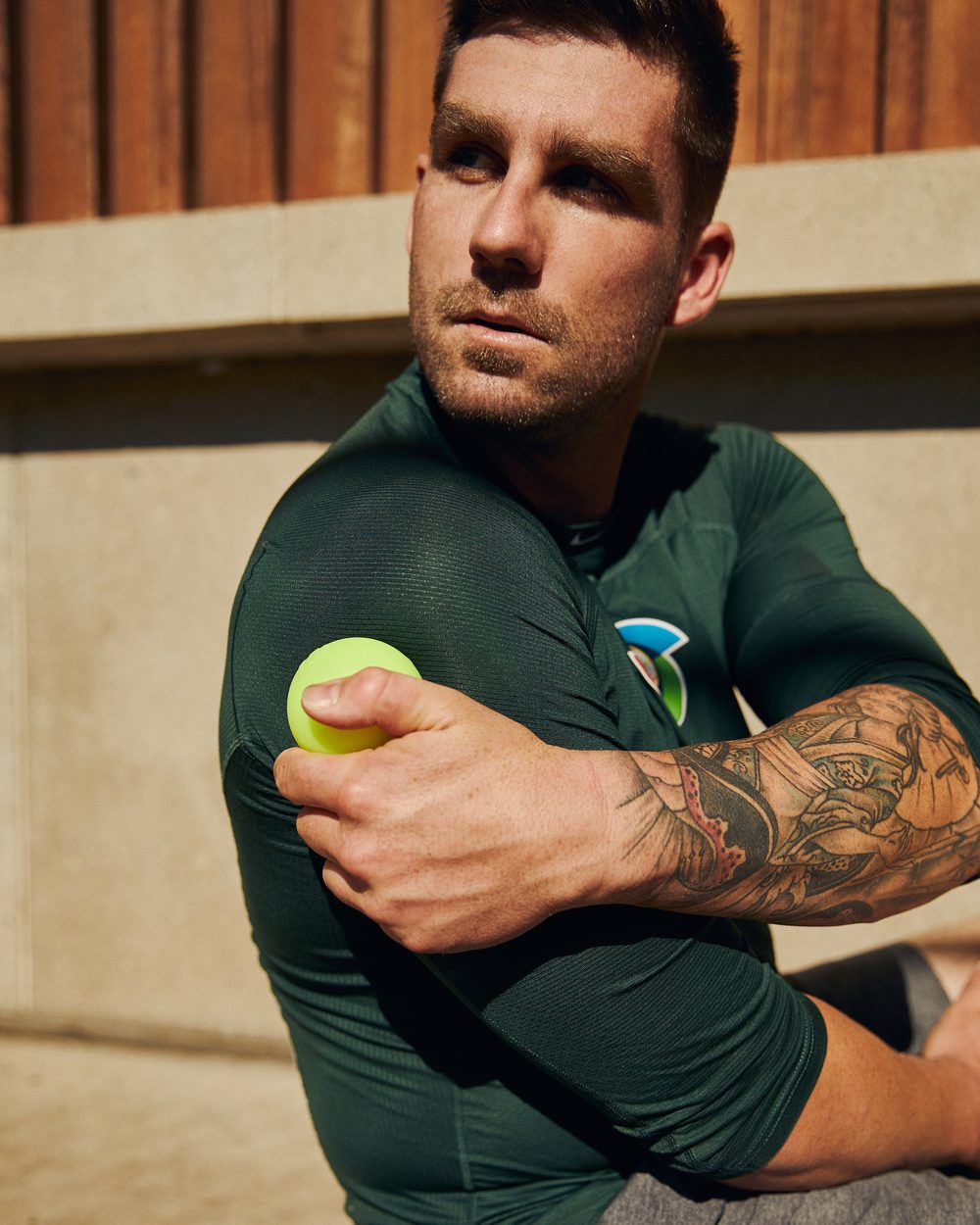 Tim Atherton in a green Australia training top pressing a lime PTP massage ball into the front of his shoulder