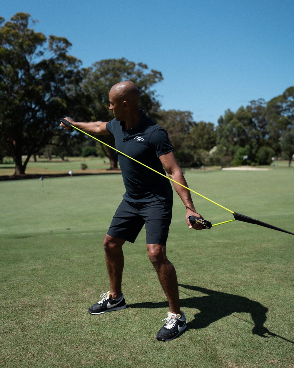 Golfer in a black PTP polo doing a tube rotation with a lime PTP Powertube+ on the fairway