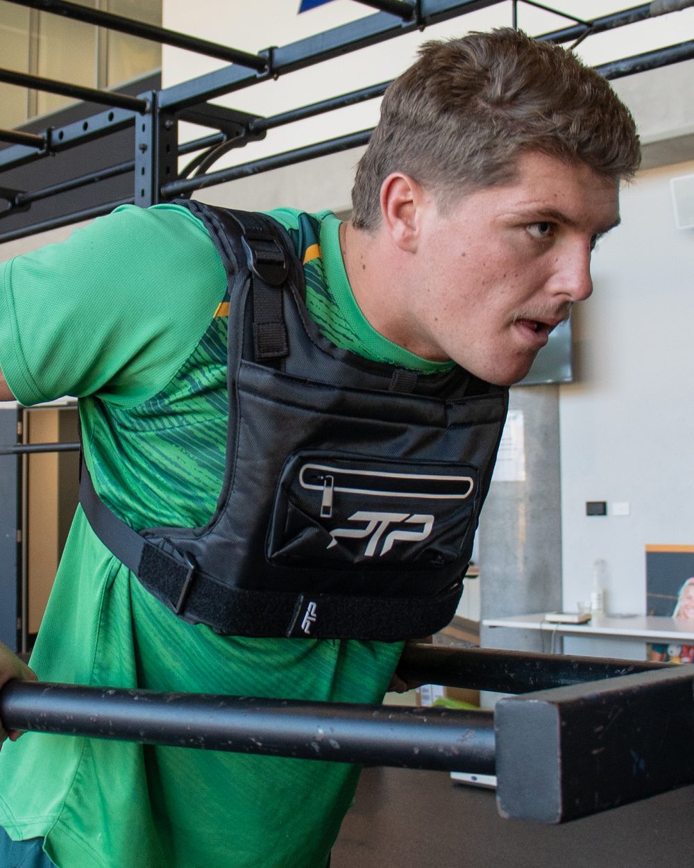 Rugby player doing a dip in the rack wearing a black PTP XGRAVT weighted vest