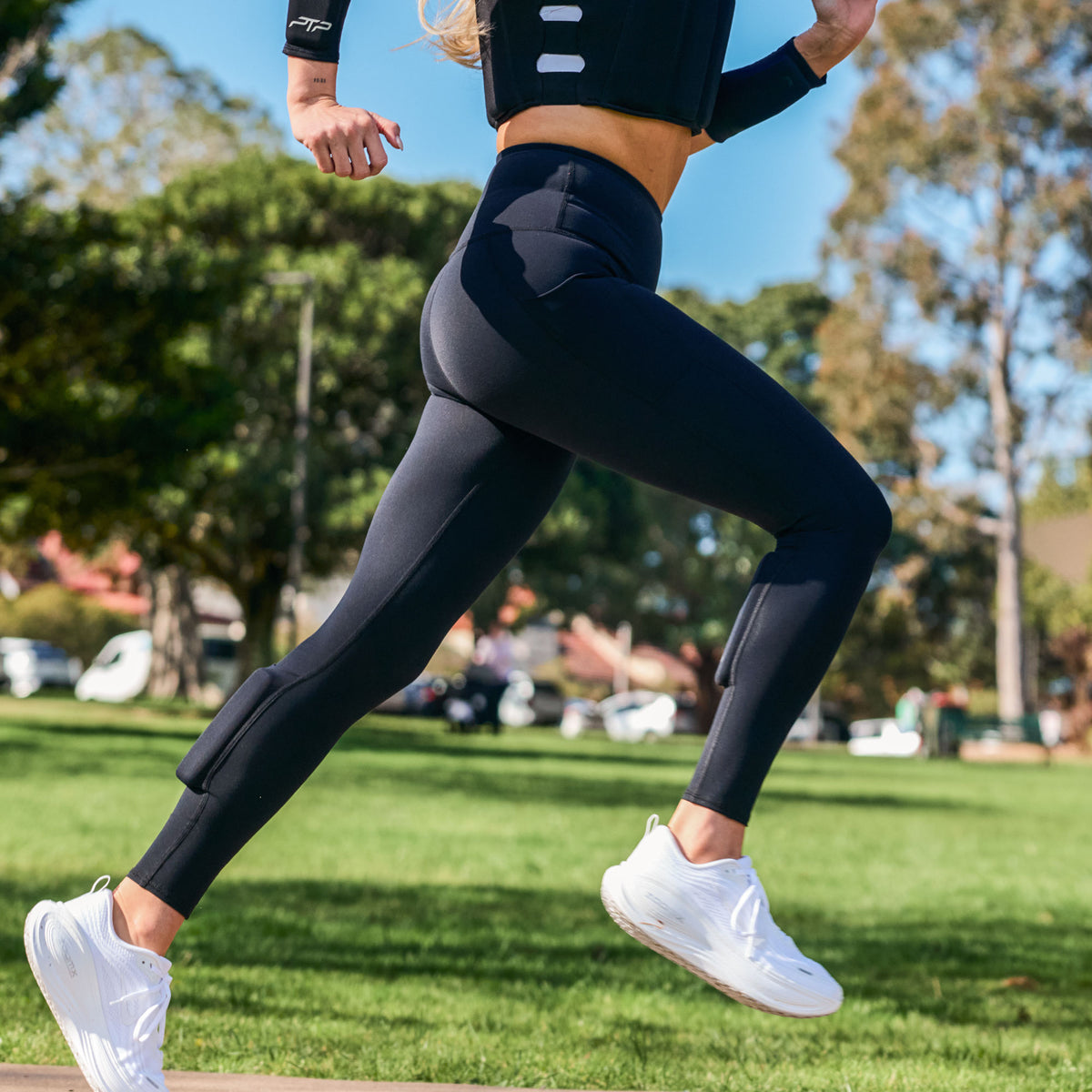 Woman running outdoors in black PTP Pace Microweighted Leggings with calf weight pockets.