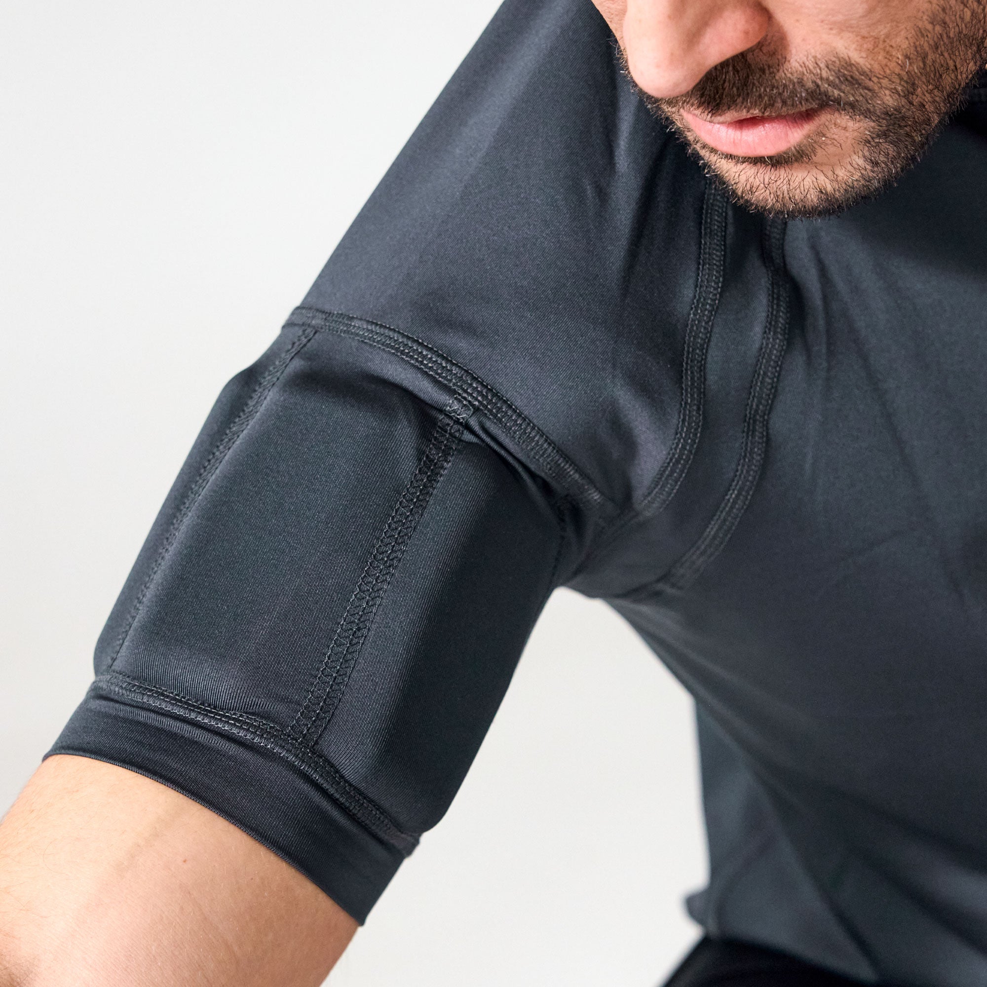 Close-up of a man wearing a dark gray athletic compression sleeve on his upper arm, showing the textured fabric and seam details.