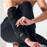 Woman wearing a black PTP Motion Microweighted Arm Sleeve while crouching in a studio.