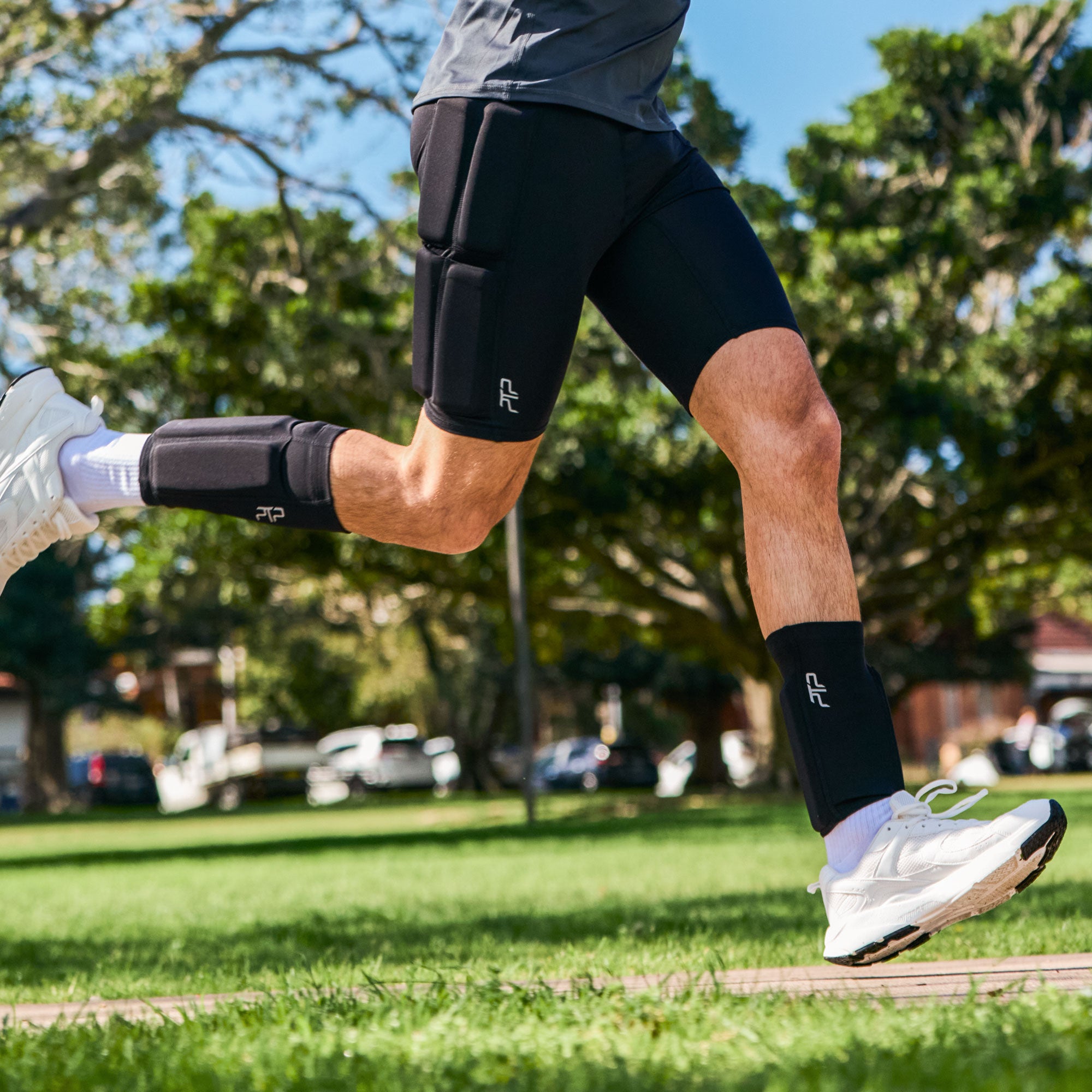 Man running across grass while wearing black PTP Motion Microweighted Calf Sleeves.