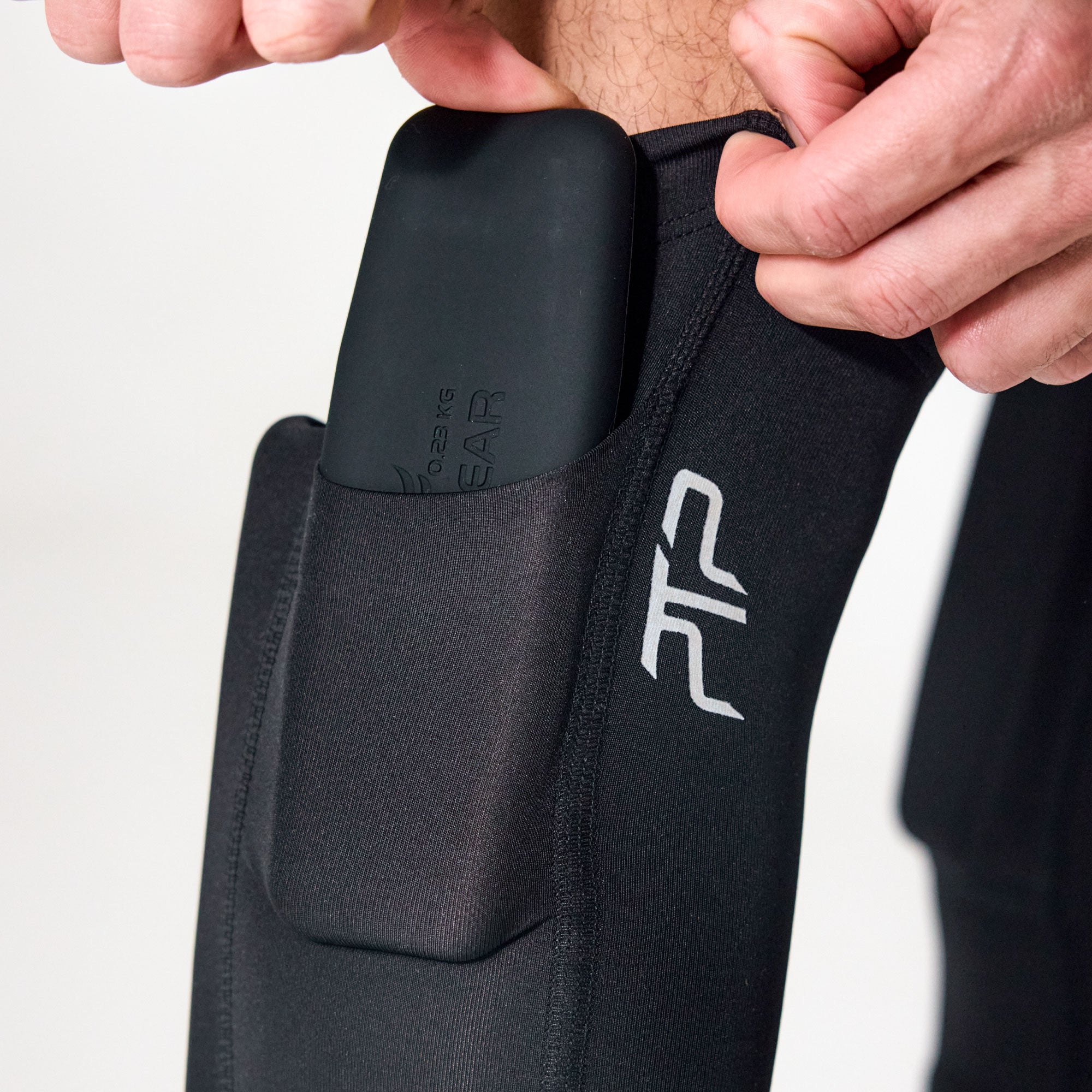 Close-up of a removable pocket weight being inserted into a PTP Motion Microweighted Calf Sleeve.