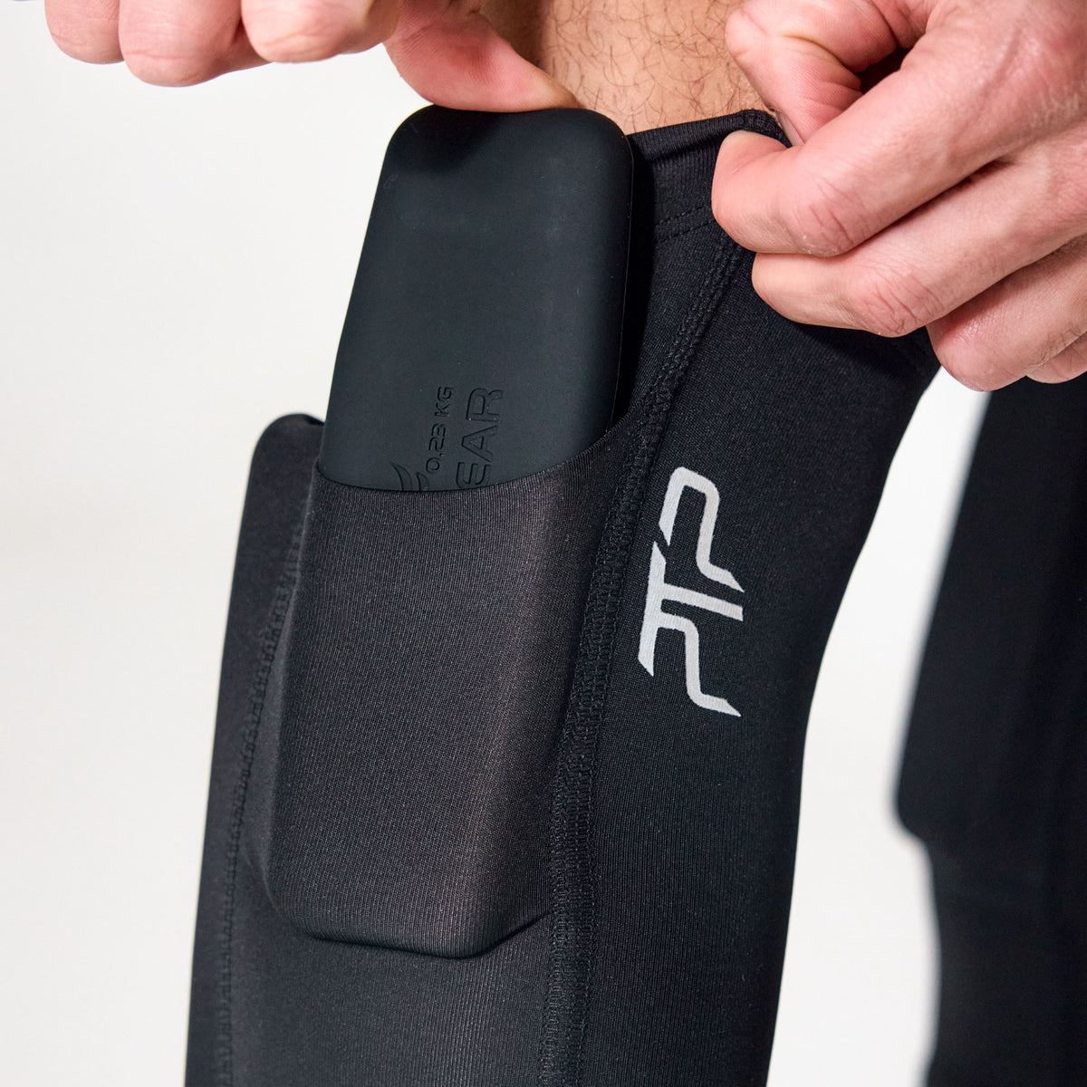 Close-up of a removable pocket weight being inserted into a PTP Motion Microweighted Calf Sleeve.