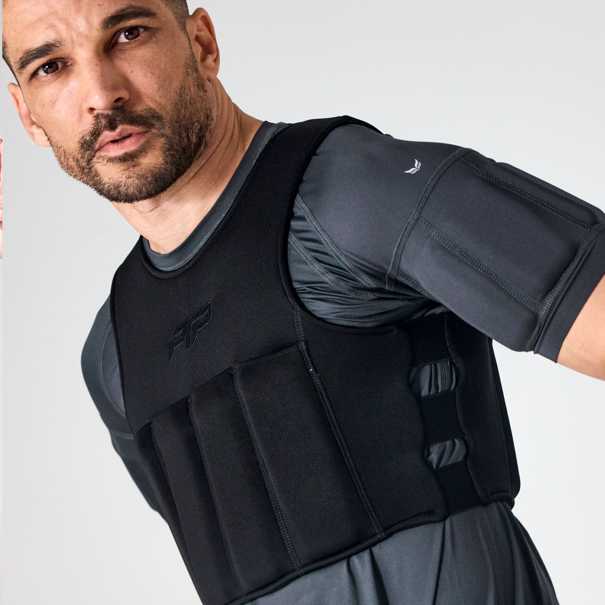 Man wearing a black PTP Plyoslide Microweighted Vest over a grey training tee.