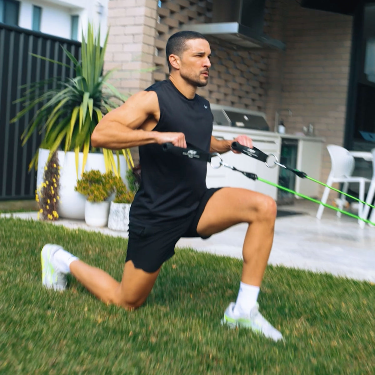 Man exercising with resistance bands in a backyard setting