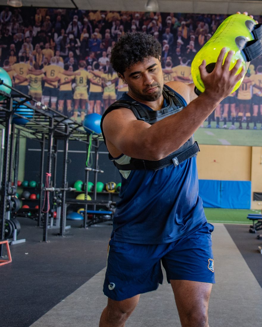 Rugby player pressing a lime PTP Aquacore overhead in the gym